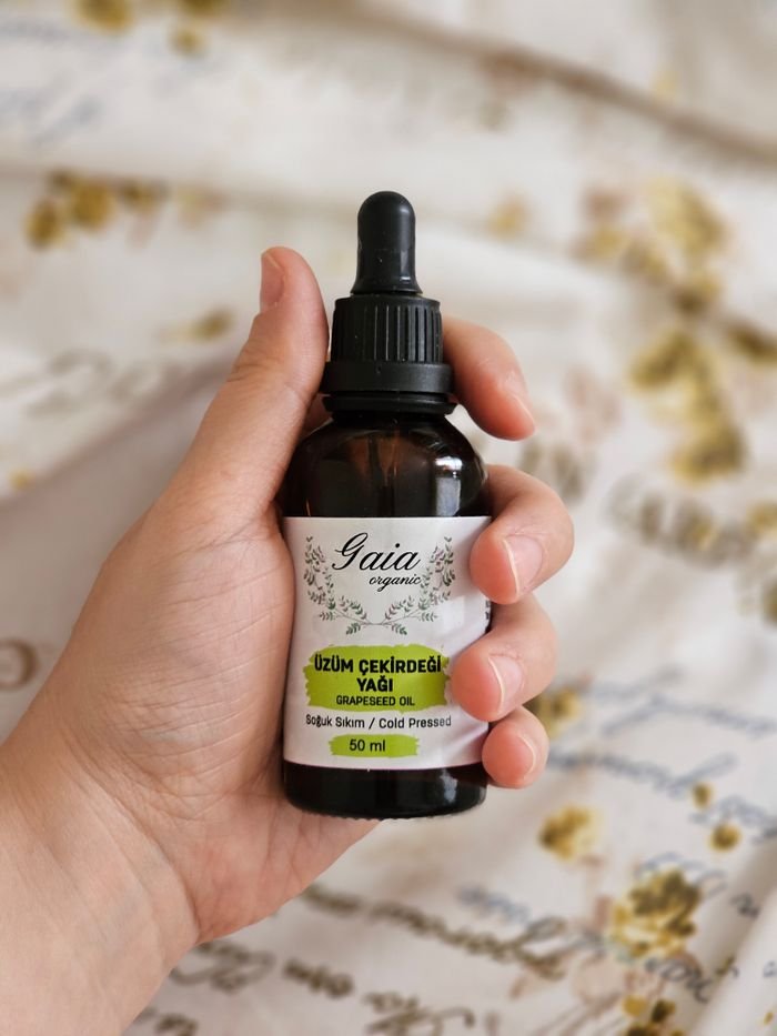 about-03 Close-up of a hand holding a bottle of Gaia organic grapeseed oil, perfect for skincare.
